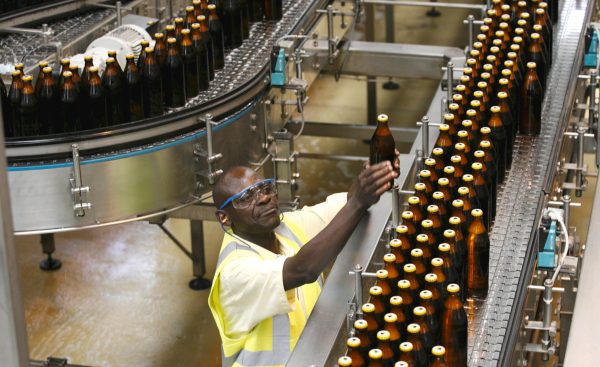 A worker inspects beer bottles on a conveyor belt at the East African Breweries Ruaraka factory in Kenya's capital Nairobi in this February 17, 2010 file photo. Kenya's East African Breweries Ltd (EABL) expects a hike in beer excise duty to hit demand in its home market in the coming months and will raise output of a lower-taxed cheap brand in an attempt to offset the impact, its CEO said on January 29, 2016. REUTERS/Thomas Mukoya/Files